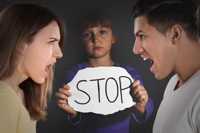 Image of Double exposure of sad little girl with sign STOP and her arguing parents