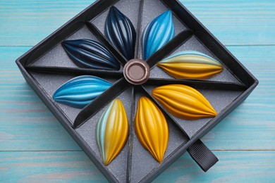 Photo of Box of tasty chocolate candies on light blue wooden table, above view