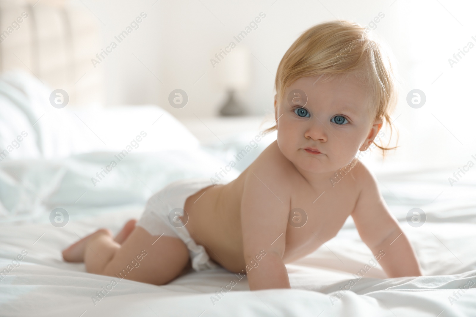 Photo of Cute little baby in diaper on bed at home