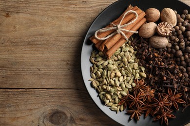 Photo of Different spices and nuts on wooden table, top view. Space for text