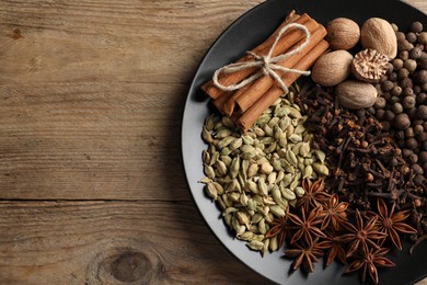 Different spices and nuts on wooden table, top view. Space for text