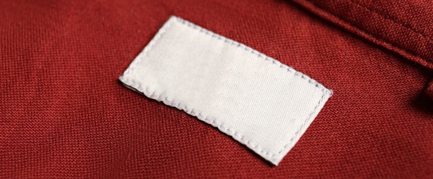 Image of Blank clothing label on red shirt, closeup. Banner design