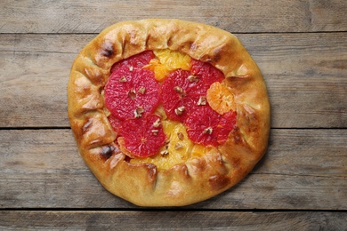 Delicious galette with citrus fruits and walnuts on wooden table, top view