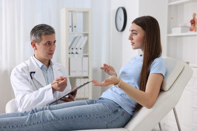 Gastroenterologist with clipboard consulting patient in clinic