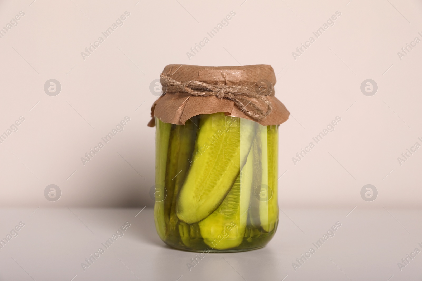 Photo of Jar of tasty pickled cucumbers on white table