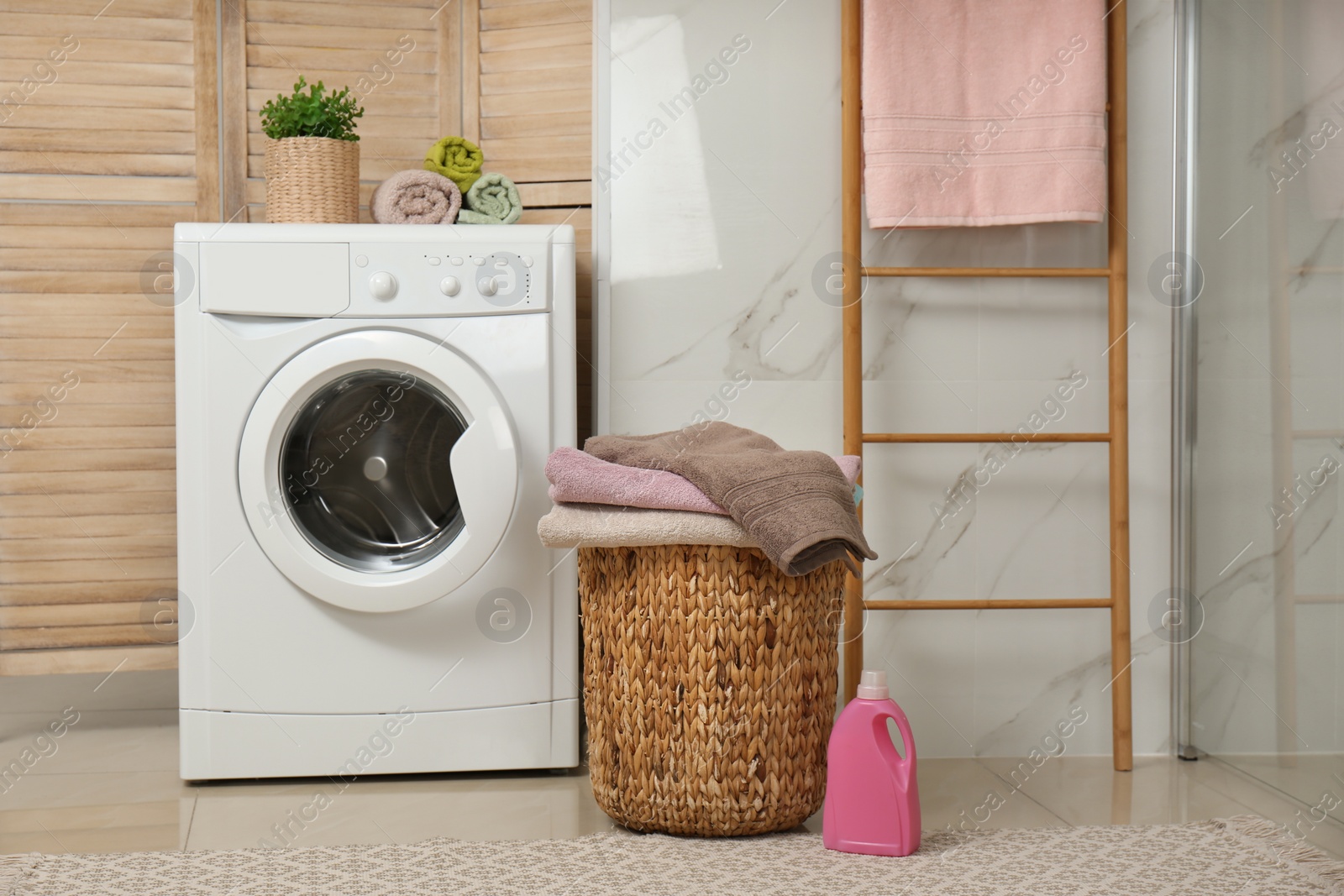 Photo of Modern washing machine and laundry in bathroom