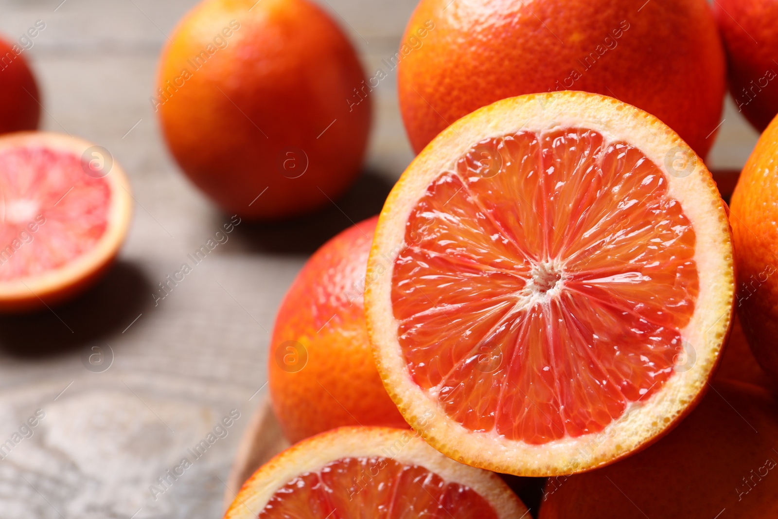 Photo of Whole and cut red oranges on wooden table, closeup