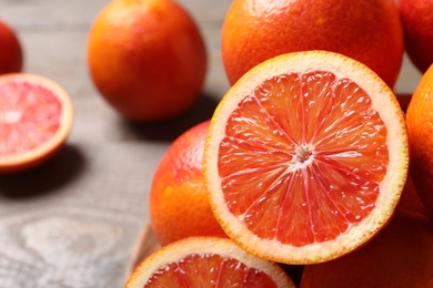 Photo of Whole and cut red oranges on wooden table, closeup