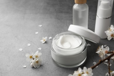 Photo of Jar of face cream and other cosmetic products on grey table. Space for text