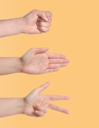 People playing rock, paper and scissors on pale orange background, closeup