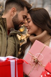 Lovely couple with Christmas presents near festively decorated store outdoors