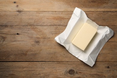 Block of tasty butter on wooden table, top view. Space for text