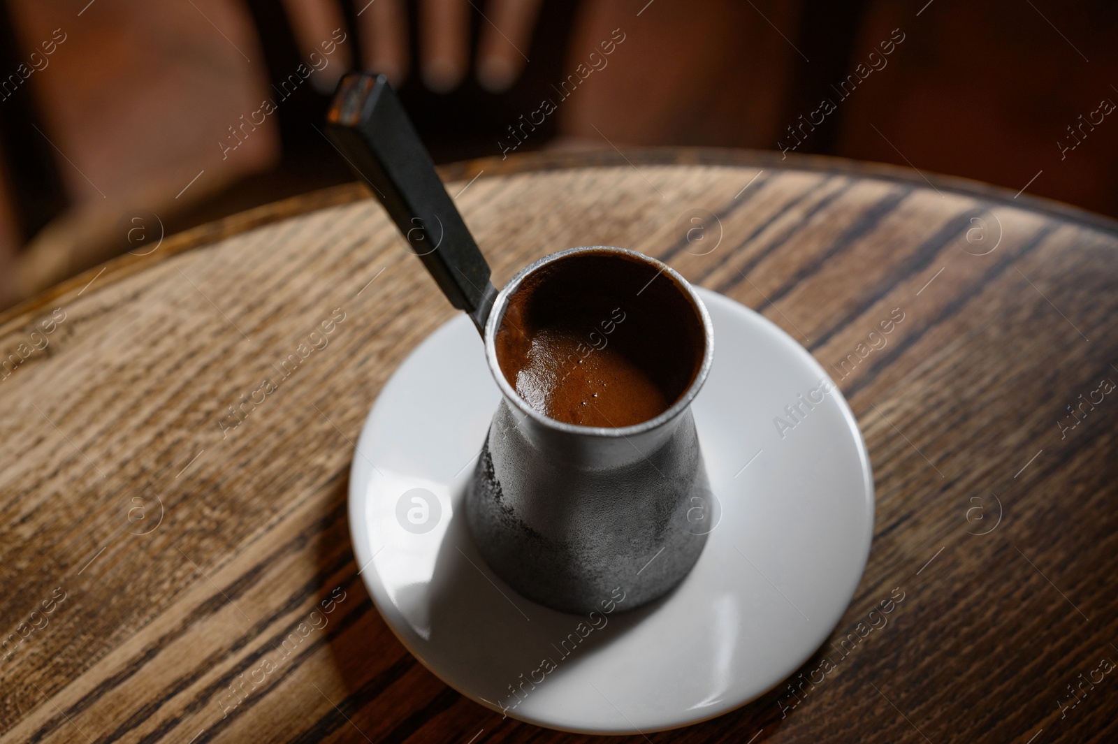 Photo of Jezve with fresh coffee on wooden table indoors