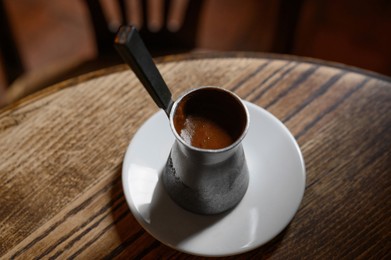 Photo of Jezve with fresh coffee on wooden table indoors