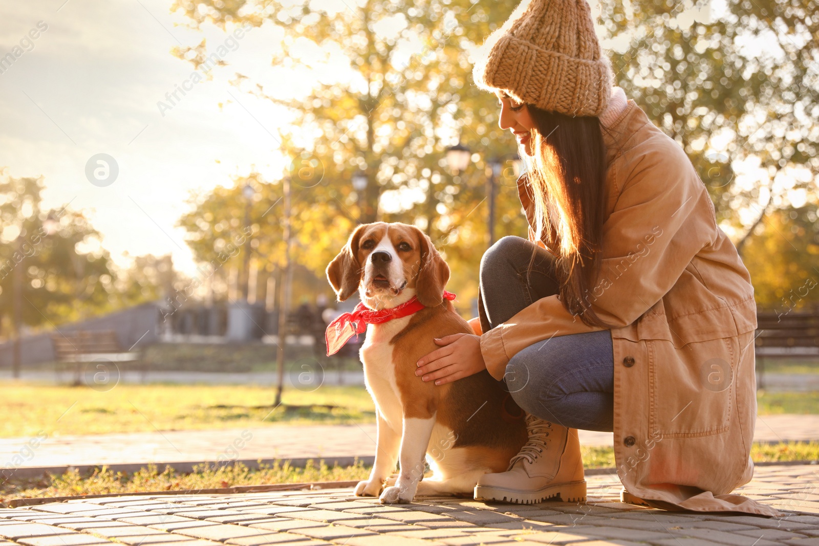 Photo of Woman walking her cute Beagle dog in autumn park