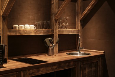 Photo of Stylish metal sink and utensils in hotel kitchen. Interior design