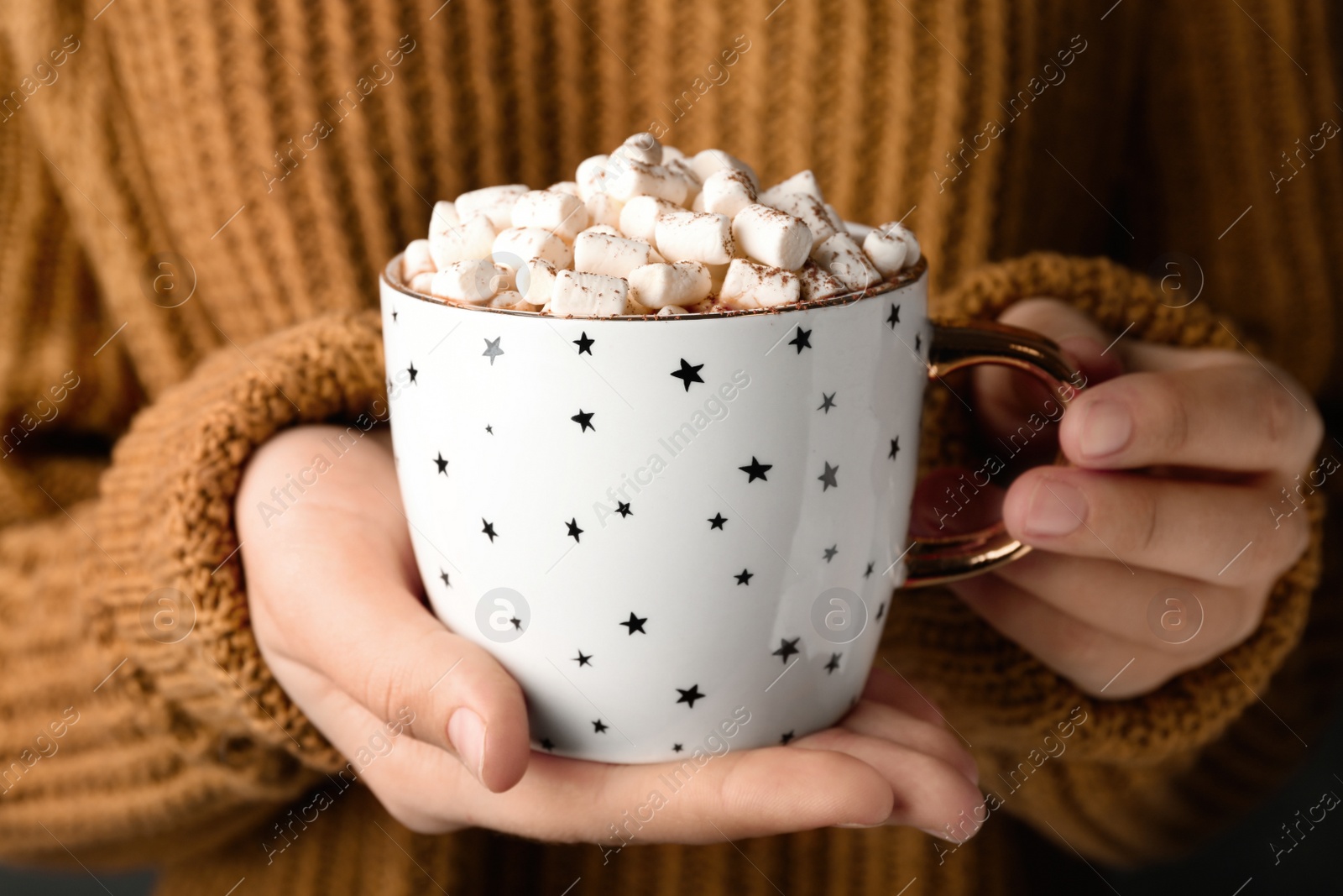 Photo of Woman holding cup of aromatic cocoa with marshmallows, closeup