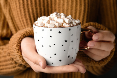 Woman holding cup of aromatic cocoa with marshmallows, closeup