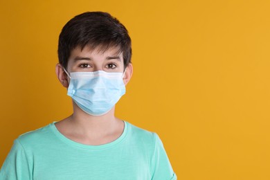 Photo of Boy wearing protective mask on yellow background, space for text. Child safety