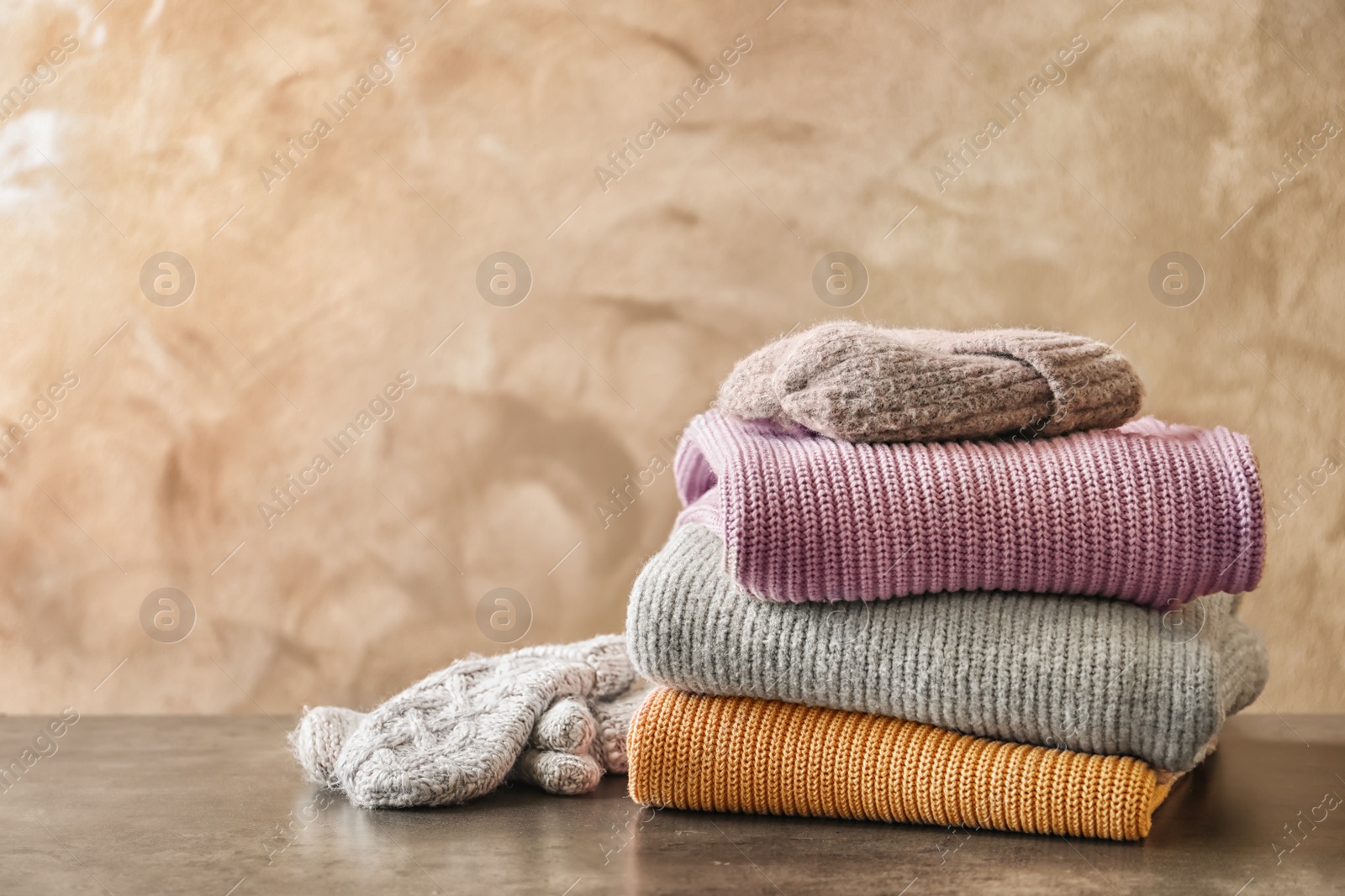 Photo of Stack of warm knitted clothes on table