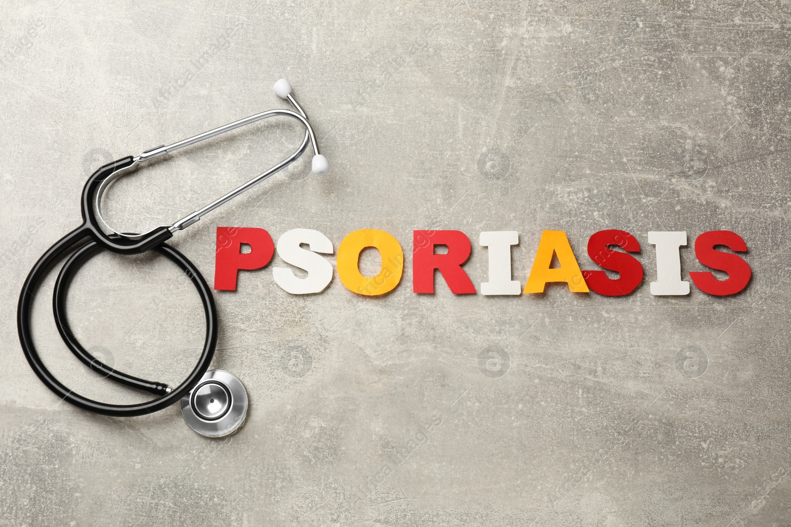 Photo of Word Psoriasis made of paper letters and stethoscope on light gray textured table, flat lay