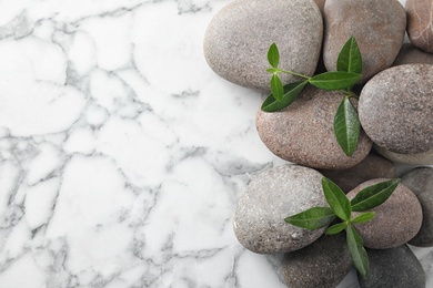 Photo of Spa stones and green leaves on marble table, flat lay with space for text