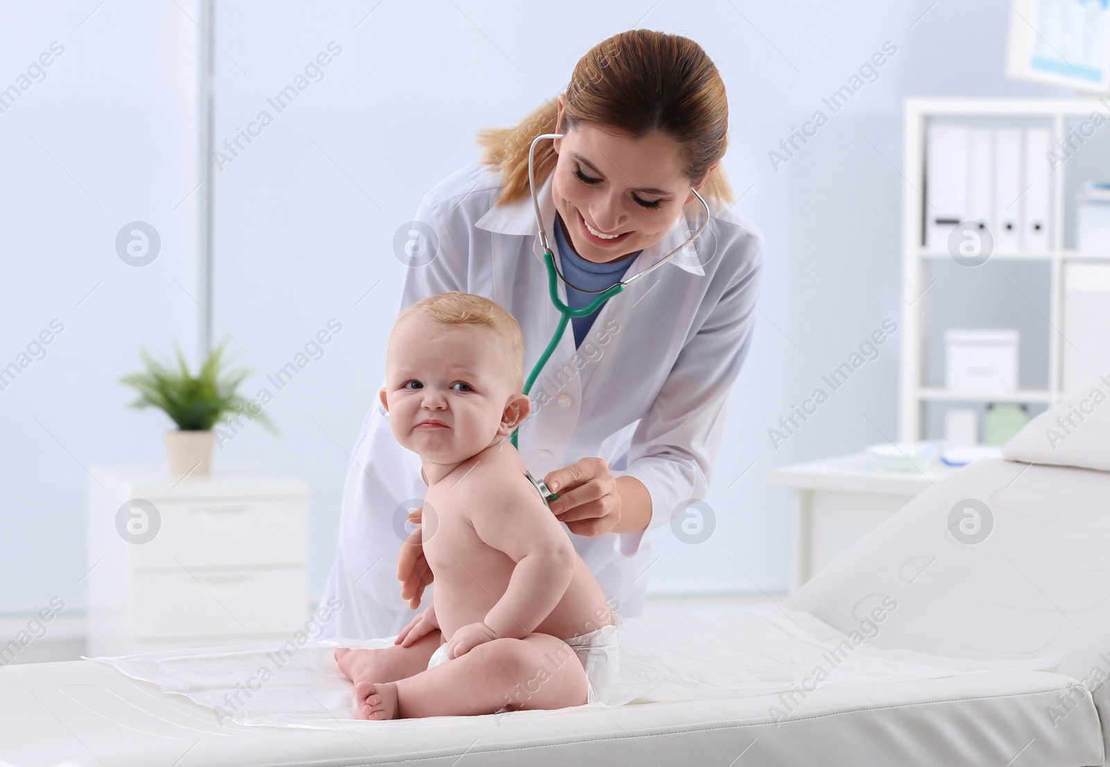 Photo of Children's doctor examining baby with stethoscope in hospital