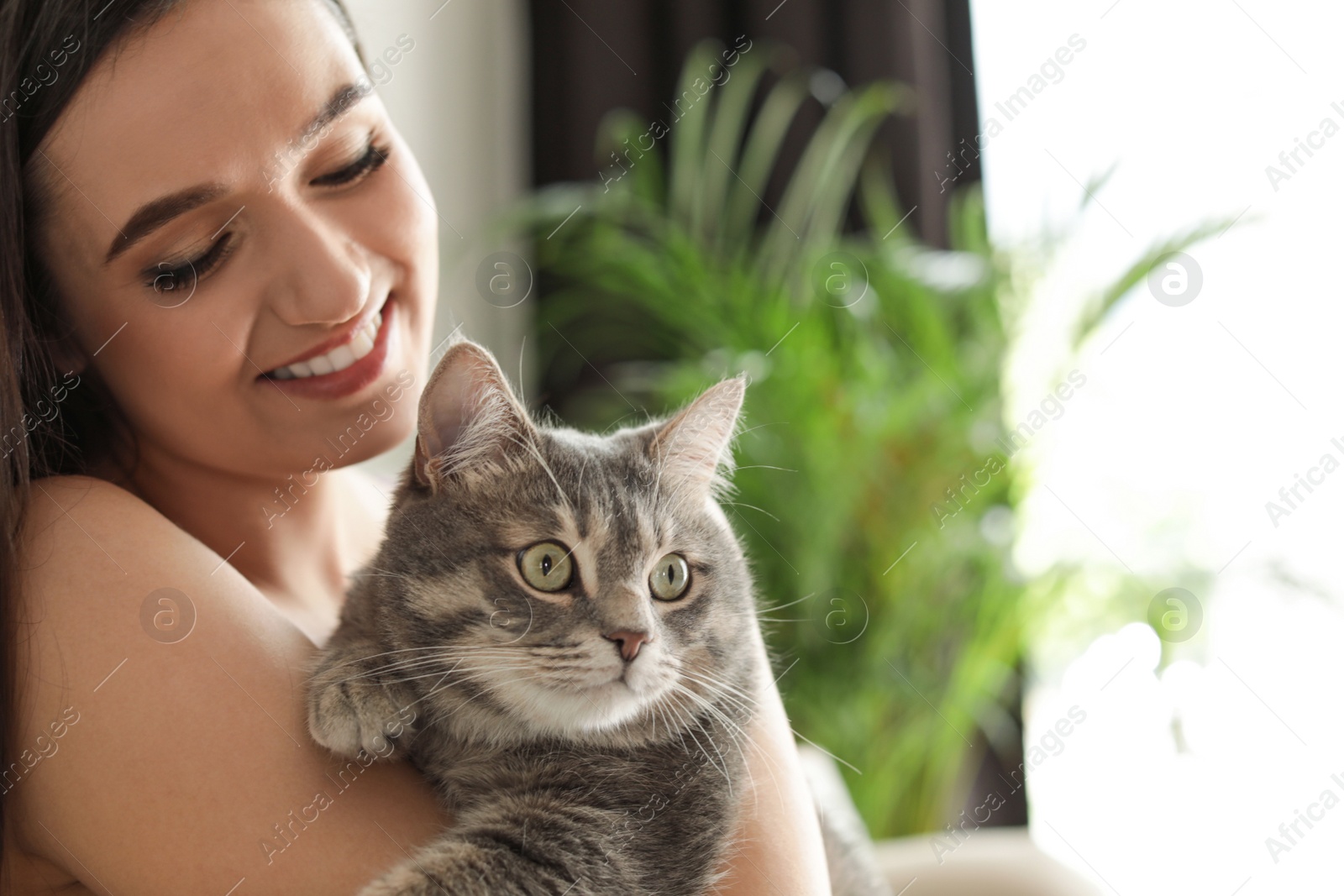 Photo of Young woman with cute cat at home, space for text. Pet and owner