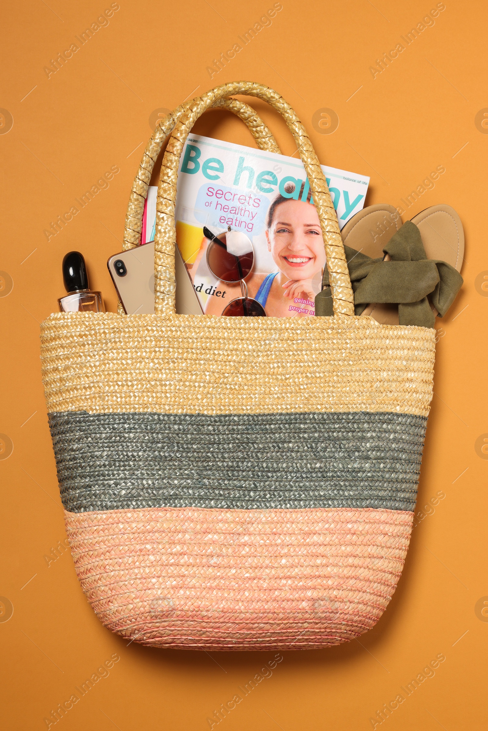 Photo of Flat lay composition with wicker bag and other beach accessories on orange background