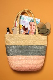 Flat lay composition with wicker bag and other beach accessories on orange background