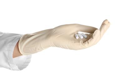 Doctor in medical glove holding pills on white background