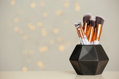 Photo of Set of makeup brushes in holder on table. Space for text