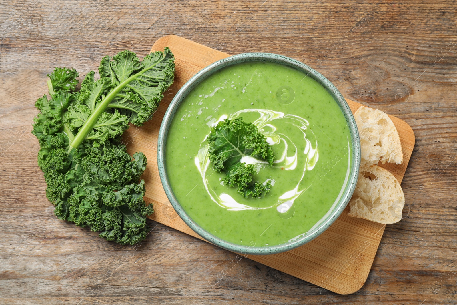 Photo of Tasty kale soup served on wooden table, flat lay