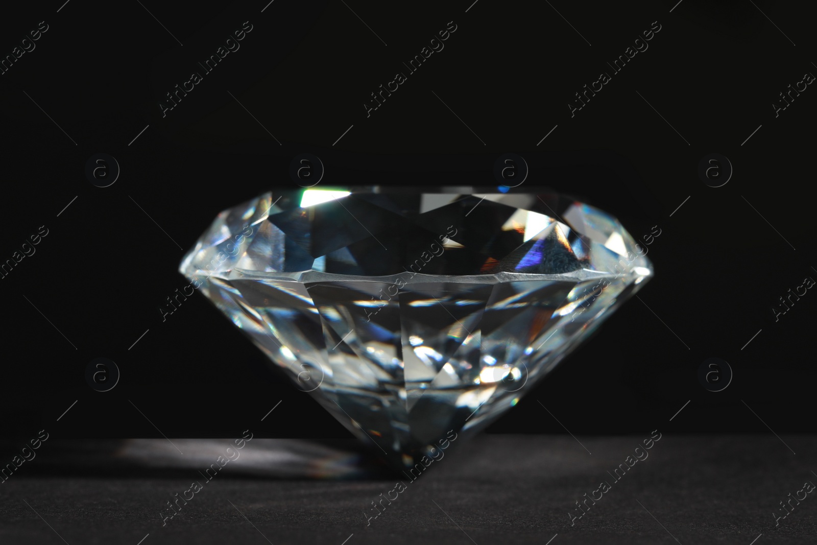 Photo of Beautiful dazzling diamond on dark background, closeup. Precious gemstone