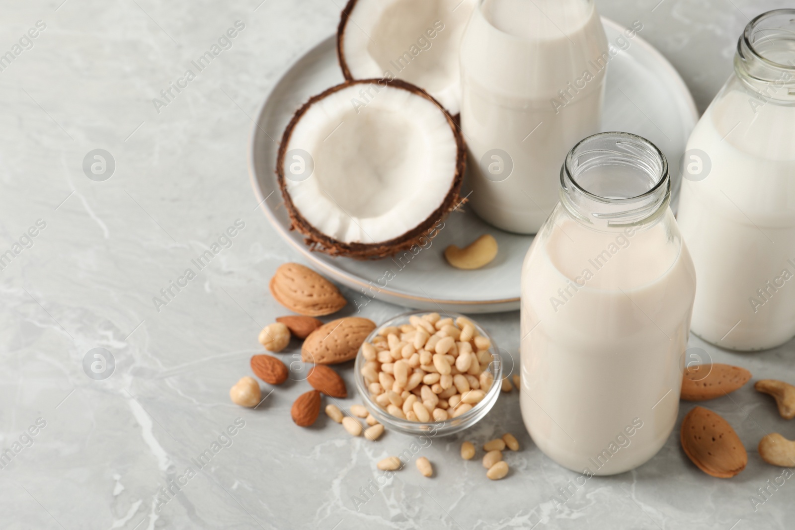 Photo of Different nut milks on light grey marble table. Space for text