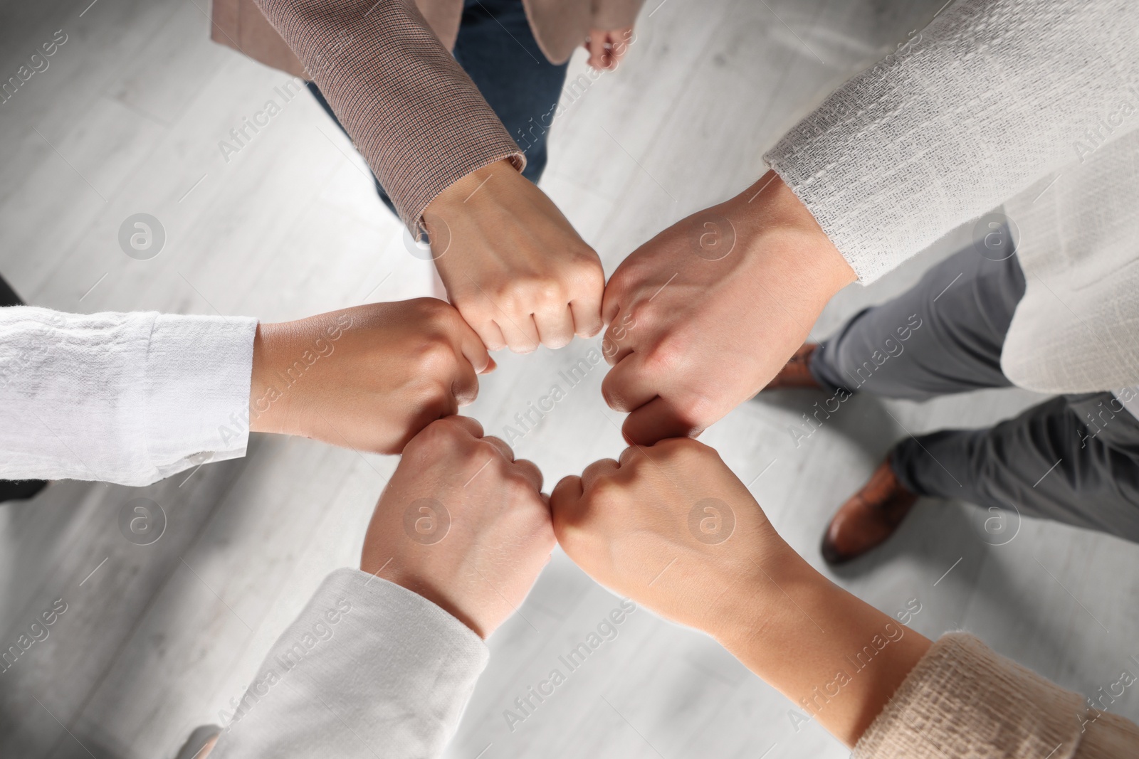 Photo of Group of people holding fists together indoors, above view. Unity concept