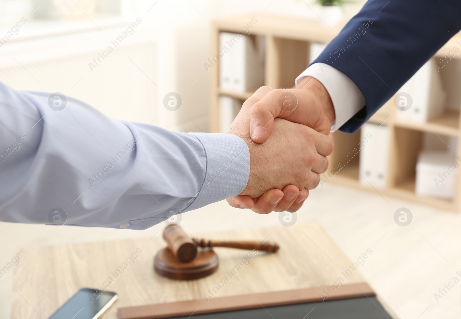 Photo of Lawyer handshaking with client over table in office, closeup