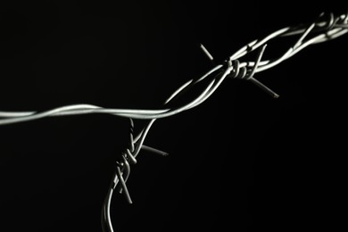 Photo of Metal barbed wire on black background, closeup