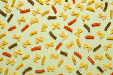 Photo of Different types of pasta on light green background, flat lay