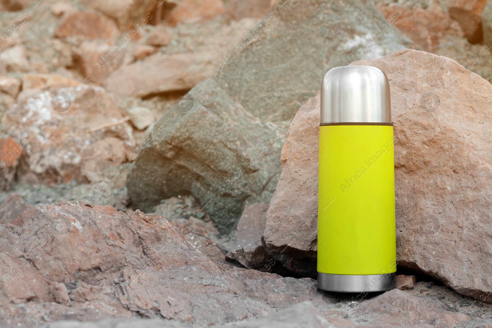 Photo of Metallic thermos with hot drink on stone outdoors, space for text