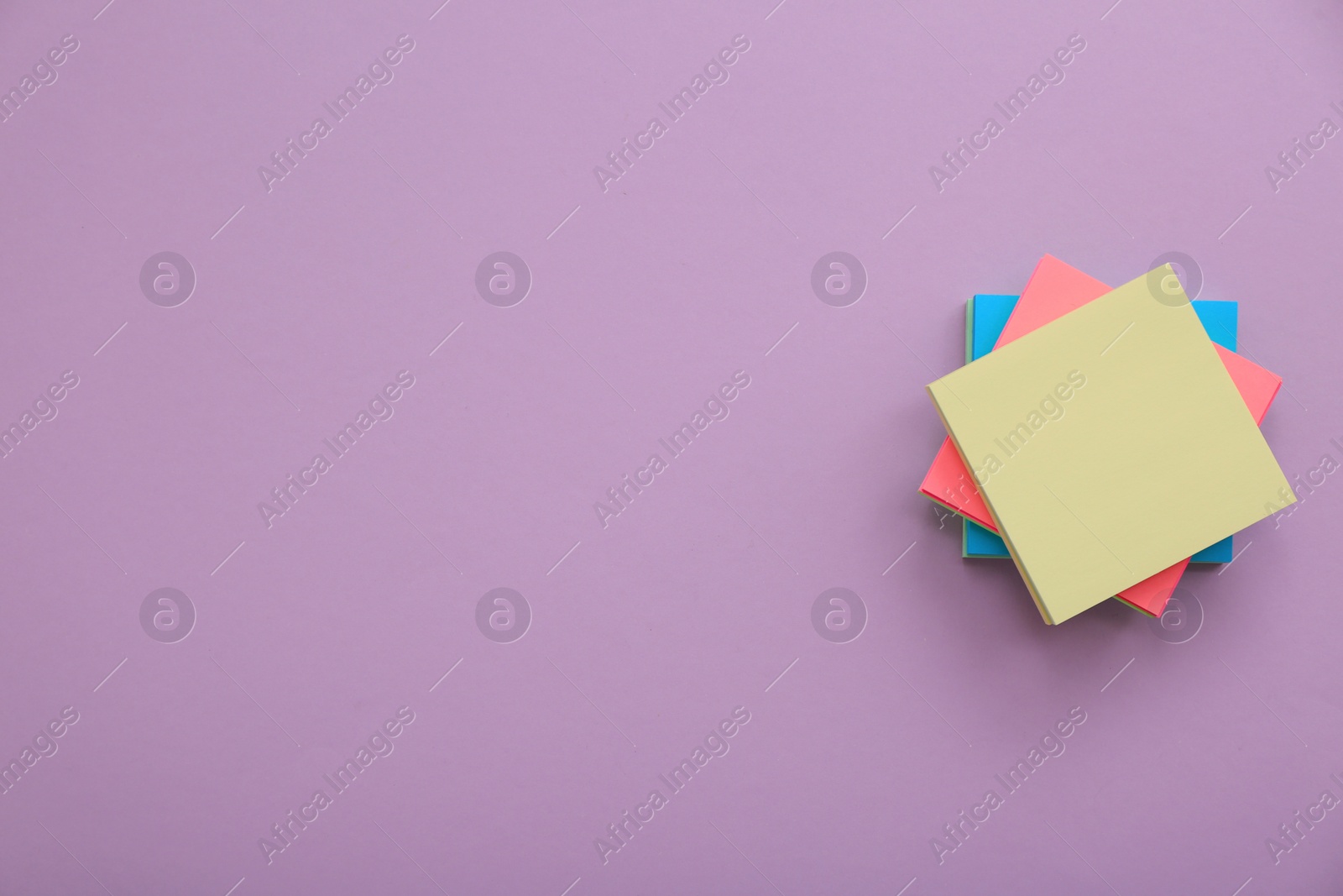 Photo of Stack of colorful stickers on violet background, top view. Space for text