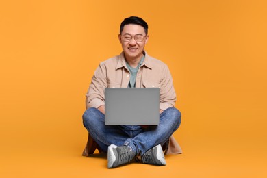 Happy man with laptop on yellow background