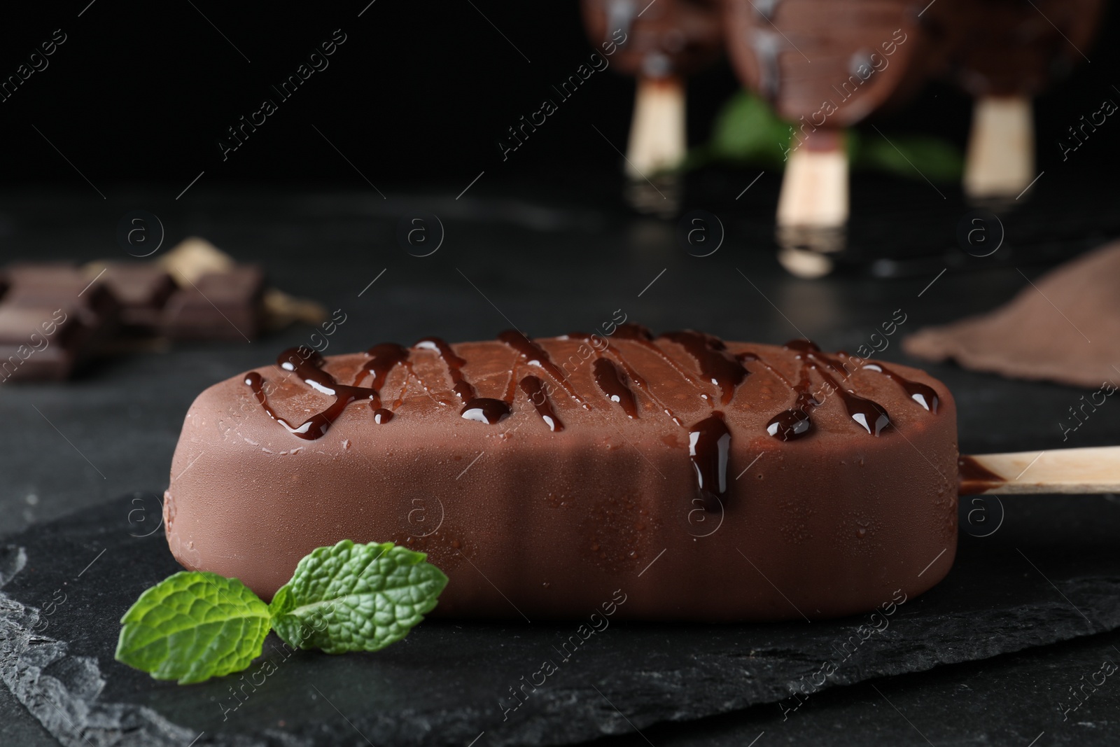 Photo of Delicious glazed ice cream and mint on black table, closeup