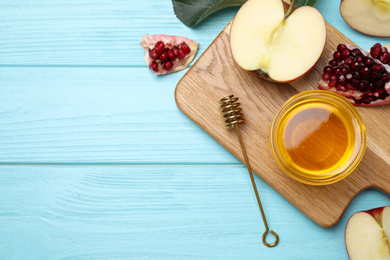 Photo of Honey, apples and pomegranate on light blue wooden table, flat lay with space for text. Rosh Hashanah holiday