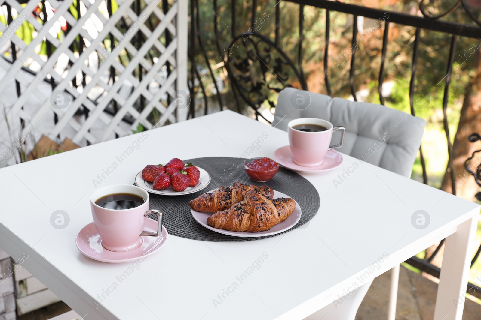 Photo of Outdoor breakfast with tea and croissants on white table on terrace