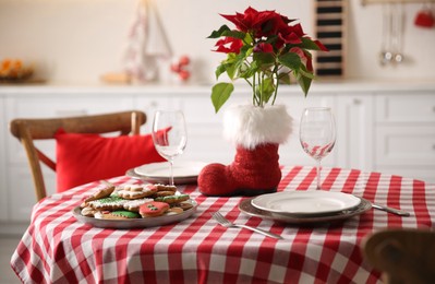 Photo of Festive table setting with Christmas cookies and Poinsettia in kitchen