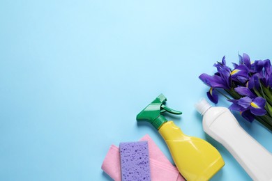 Photo of Spring cleaning. Detergents, flowers, sponge and rag on light blue background, flat lay. Space for text