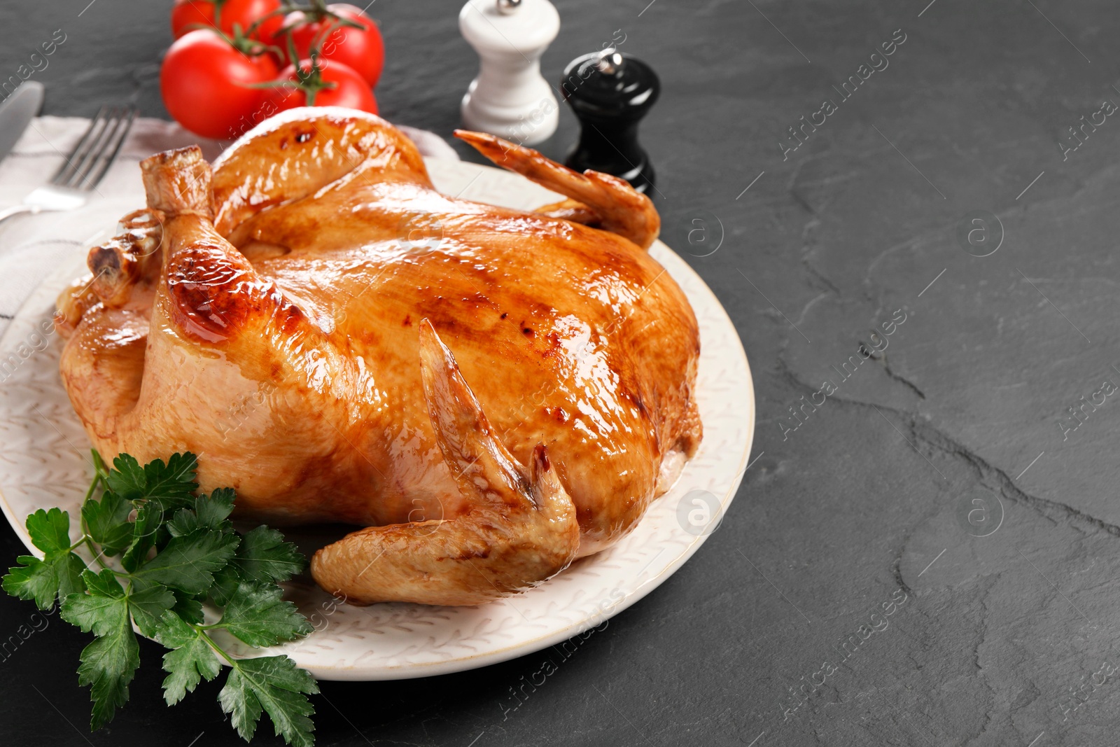Photo of Tasty roasted chicken with parsley served on grey textured table, space for text