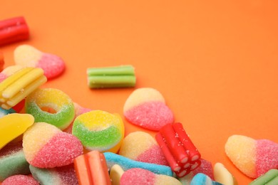 Photo of Many different jelly candies on orange background, closeup. Space for text
