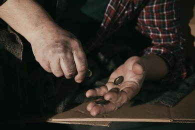 Photo of Poor senior man counting coins on cardboard, closeup